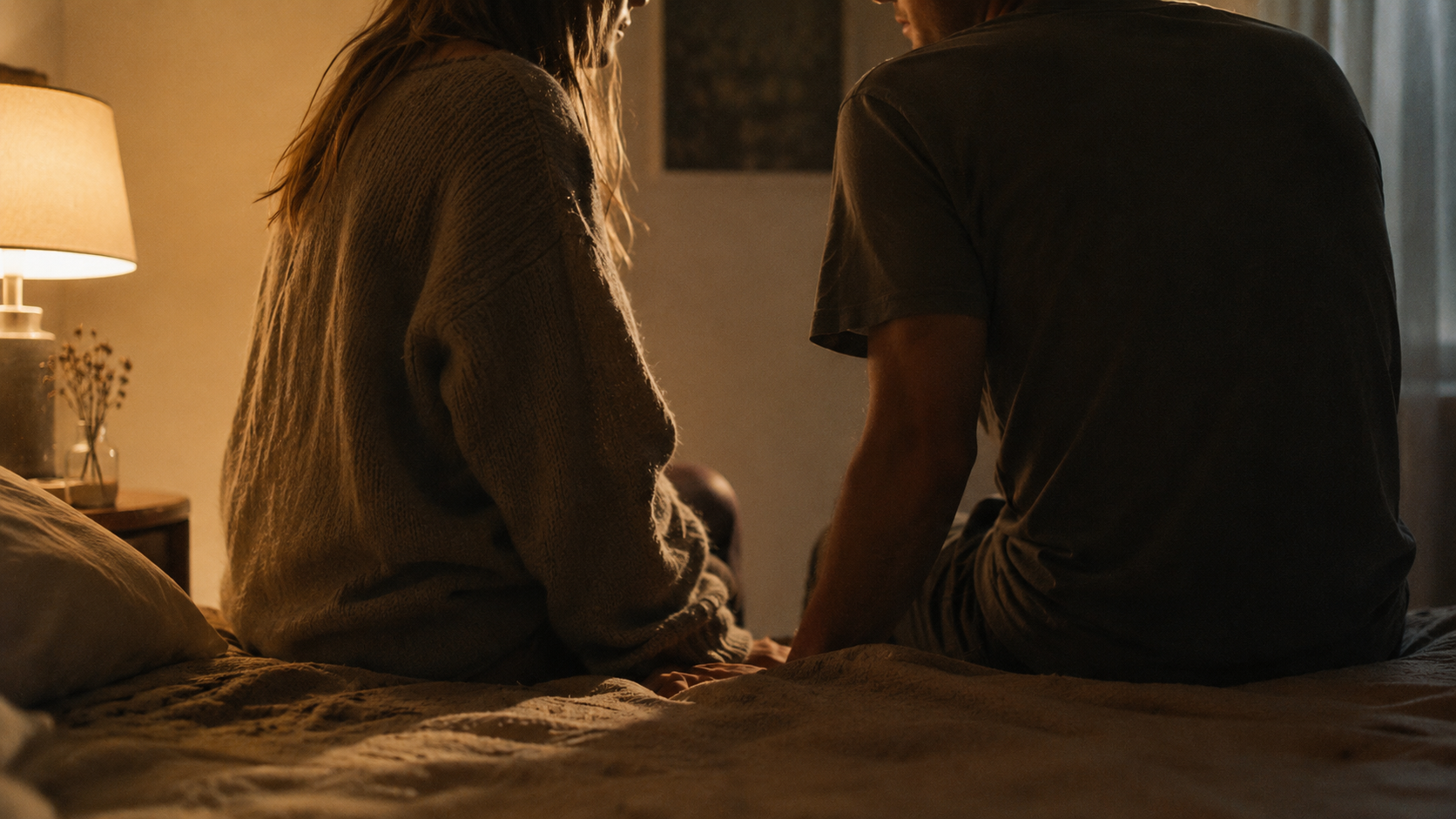 Two people sitting close together having a quiet, focused conversation in a softly lit room.